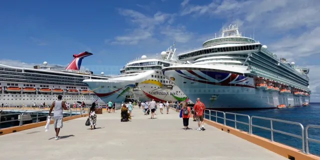 Three large cruise ships docked side by side at a sunny port in Mexico.